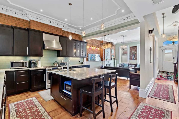 Rare opportunity in Downtown Jersey City to own this historic two family brownstone with parking! Built in 1880, the home was renovated in 2011 to convert from a four family to a two family with all new electric and plumbing, central air, and many other modern upgrades. 20 ft wide and tastefully appointed with a mix of classic original features such as crown mouldings, wide plank hardwood flooring, and exposed brick walls and chimneys, alongside modern amenities like central air, washer dryer, and modern kitchen and bathrooms. Live in the owner's triplex and rent out the ground floor apartment, or keep it as an in-law's suite. Enter the home into the parlor level and you'll find the living room which flows into the kitchen in an open floor plan. High ceilings with decorative trim, chandeliers as well as recessed lighting, lots of exposed brick, and room for a dining table. Half bathroom on this level with yet more exposed brick. The chef's kitchen has an abundance of cabinet space and long granite countertops, along with an island in the middle. Upstairs each floor provides two large bedrooms, an additional bedroom/office/den, and a full bathroom, bringing us to six bedrooms and 2.5 bathrooms. The bedrooms have large walk-through closets between them. One bathroom as a bathtub and the other has a custom made glass enclosed steam shower. The rear windows overlook the backyard as well as The Embankment, which is slated by Jersey City to become a park with the inspiration of Manhattan's High Line. There is a carriage house type of structure in the back of the yard which has electricity and makes a great additional space for a variety of uses. The ground floor apartment is a one bed one bath with optional backyard access. Building an extension to the back of the house is permitted. Parking in front of the house is the icing on the cake. Inquire today for a virtual or in-person tour. Check out the 3D Virtual Tour: bit.ly/206virtualtour