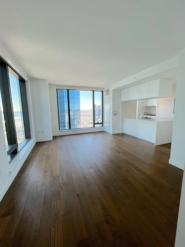 Beautiful views of NYC and the Hudson river greet you in this beautiful home high in the sky, in the luxurious 99 Hudson building on the Jersey City waterfront. Enjoy a modern and open-concept layout between the living space and the kitchen, with floor-to-ceiling windows flooding the home with natural light. The kitchen features custom white cabinetry imported from Italy that provide plenty of storage, stainless steel appliances and Kohler fixtures, vented Italian hood, and waterfall island with quartz countertop. Bathroom features custom wood vanity, quartz countertop, Kohler fixtures, imported ceramic Statuario flooring and wall tiling, and a large tub with rainwater showerhead. Bedroom features windows to two exposures and a large double door closet. Add to this wide oak flooring throughout the home, high performance insulation windows, energy-efficient heating and cooling, Bosch laundry machines in unit and recessed lighting. Enjoy this new, full-service amenity building with 24-hour concierge, state of the art fitness center, pool with cabanas, children's playroom, billiard's room, theater room, Residents Lounge, golf simulator, dog run and a location that is great for strolling to everything! Add proximity to PATH & Ferry, plus CitiBikes & Light Rail, and this is your ideal home!