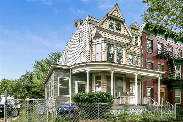 This Folk Victorian home built in the 1880s/1890s is located in one of the oldest continually occupied portions of the city (Bergen Hill) and has original front doors, a partially enclosed wrap-around porch (enclosure is post build), second story window sashes and roofline. This historic home sits on a double lot (52.34'x100') complete with a full drive way and room for at least 3 cars and includes a spacious double backyard. The interior (first floor) of this home includes original plaster moldings and medallions, two sets of working 8 1/2 foot pocket doors, a showpiece decorative fireplace and mantle and much of the original woodwork (including wainscoting) that is gorgeous, intact and in excellent condition. The second floor has 3 bedrooms including a spacious master bedroom and a full bathroom. The third floor has an additional full bathroom, a kitchenette and two more bedrooms, plus an unfinished space that can be used as attic storage or add your finishes for a huge bonus room. The unfinished, walkout full basement has a working (non-buried, above-ground) oil tank as well as access to the backyard. Close to Journal Square PATH and Summit Ave bus lines to JSQ and NYC are at the intersection.