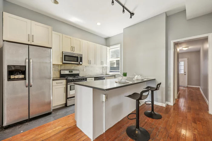 Investment Opportunity! Located just a short walk from Journal Square, this fully renovated Jersey City home offers an exceptional living experience. Featuring four (4) bedrooms and two (2) full bathrooms, the property boasts an open-concept layout perfect for gatherings and entertaining. On the first floor, you'll find a living and dining area, a modern kitchen with stainless steel appliances and granite countertops, a stackable laundry closet, a full bathroom. The second floor hosts four (4) additional bedrooms, another full bathroom, and a dedicated office space. Gleaming hardwood floors run throughout the home, and large windows flood the space with natural light. Outside, the private backyard provides a serene retreat for relaxation and outdoor activities. Additional features include a partially finished basement, ideal for extra storage use. This prime location offers walking distance to Journal Square, providing easy access to PATH trains and bus routes for quick commutes to Manhattan and beyond. Close to shops, restaurants, and parks, this home is perfect for those seeking both convenience and luxury. Property will be sold with active lease- Lease expires August 2025