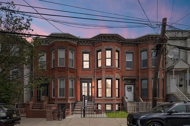 Welcome to your restored Bergen-Lafayette Brownstone next to all major transportation into NYC! This home features maximum curb appeal with red brick facade and custom black frame windows. Enter the parlor level to find a dramatic white oak staircase, a completely modern home with restored historic features such as plaster corbels, four original decorative fireplaces, brand new herringbone floors throughout and designer powder room. The modern kitchen has sleek midnight blue cabinetry, quartz counters and quartz backsplash, with stainless steel appliances. Off the kitchen enter the backyard with privacy fence, mature tree shade coverage, and no-maintenance turf. The second floor features a primary suite with ensuite bath, 4 large sun-filled windows, and decorative fireplace. Two more spacious bedrooms, a full bathroom, and full-size washer/dryer complete the second floor. The lower level features a bonus space with private entrance, wet bar, study/den, perfect for AirBnb. Seller providing credit for **One Year of Rental Parking** Directly Across the Street. *This home is zoned a 2-Family, currently setup as a 1-Family home* Reach out to our preferred lender Jackie Koven for special financing programs, offering $8, 000 to $22, 000 grants for down payment assistance or closing costs.