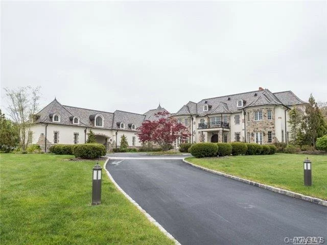 Standing majestically on well over 5 magnificent acres on what was once part of the du Pont estate, this enchanting young stone and stucco, 8-bedroom, 11-full bath, 4-half-bath, French chateau is truly an architectural masterpiece. Combining the grace and charm of “Old World” design with all the luxury and high-tech amenities so sought after today, it provides the ultimate venue for opulent “Gold Coast” living. Approached through iron gates off a quiet cul-de-sac road, populated by equally grand estates, a long winding drive leads to a circular courtyard. One can’t help but notice the graceful slate roof wrapping around various towers and turrets and the imposing front portico with massive hand-carved entry doors.  An arched porte-cochere leads through a wing of the manse to a large service courtyard and attached 4-car garage. No expense has been spared in creating this magnificent residence, from its Brazilian cherry floors and hand-carved mahogany doors to its “Smart House” technology allowing effortless control of security, telephones, intercom, sound system, water filtration and more. Every room has been impeccably designed to create an inviting and comfortable space with exquisite ceiling, wall and window treatments. 

LOCATION
Originally purchased in the 1600’s from the Matinecock Indians by early settlers, the Cedar Swamp territory east of Hempstead Harbor became a farming community of mostly English and Dutch corn farmers whose descendants sold their produce to a corn starch factory in nearby Glen Cove.  By the turn of the Twentieth Century, many magnates and financiers were drawn to the area to build their grand estates.  Today, the gentle rolling and wooded hillsides of Brookville are dotted with beautiful properties. According to Bloomberg News, Brookville is, the wealthiest community in the nation. Their residents enjoy a great location convenient to boating, golf, equestrian facilities, quaint village shopping, museums, the award winning Jericho School District, and the Long Island Railroad putting them within a comfortable 30-mile commute to Manhattan.  

DuPont Estates is a gated enclave of 7 properties encompassing approximately 53 acres that were, at one time, part of the Alfred I. DuPont 101-acre estate. Built in 1917, his mansion, “White Eagle” and the entire estate was sold in 1971 to New York Institute of Technology, which has its Old Westbury campus next door to the property. The institute kept the mansion and surrounding property for its use but sold the remaining acres, which are now DuPont Estates in the early 21st Century. Paying homage to the original estate, these new grand mansions and their secluded and gated properties are the epitomes of grand and gracious North Shore living.

PROPERTY
Acres of sweeping emerald lawns edged by gorgeous raised beds of flowering shrubs and trees give a sense of endless domain to this breathtaking property. Ideal for summer entertaining on a grand scale, the estate includes an almost hidden tennis court backed by pristine woodland and a fabulous entertainment complex. Its expansive granite terrace connects a freeform heated Gunite pool, spa, and waterfalls with a romantic pavilion with attached cabana and bath, and flanked by a circular outdoor kitchen with refrigerator and sink and by a courtyard with built-in grill and fireplace. A short walk away, a meditation hut and a koi pond provide a spot for quiet reflection. Extending across the rear of the house, a spacious bluestone patio provides easy access from the principal rooms to the outdoors, ideal for al fresco dining and relaxing. At one end, a patio off the living room enjoys views of a nearby reflection pool, and at the other, a sunken terrace with fireplace provides access to the lower level’s entertainment rooms and pub.

Offering ample space for service vehicles or valet guest parking, a large courtyard is accessed from the front courtyard through a porte-cochere that separates the stalls of the attached 4-car garage.  Estate fencing, electronic gates plus extensive outdoor lighting and security systems are practical additions.

RESIDENCE
Sunlight, entering through a 2-story wall of windows, dances across the radiant heated, inlaid crème marble floors in the ethereal entrance foyer. Here is featured a custom floor medallion echoing the design of a domed ceiling above an Italian crystal chandelier. A graceful floating staircase with filigree balustrade is accented by sconce-lit fielded paneling. Adjoining this area are an elevator, cloak room, powder room and gallery accessing the living and dining rooms and an inviting library with fireplace and French doors opening to the rear terrace. Also opening to the terrace and to its own separate patio, the striking and spacious living room features harlequin designed wall coverings, an impressive marble fireplace, gleaming inlaid floors and massive crown moldings. Eighteen-karat gold adorning the ceiling and fielded panels helps to create a stunning venue for elegant repasts in the formal dining room, which enjoys a panoramic view of the rear property through a huge bay window.

Connected to the dining room through a butler’s pantry, the spectacular gourmet kitchen is a chef’s dream. Marble-topped custom cabinetry continues the harlequin theme.  A center island boasts a farm sink, 2 butcher blocks and seating area. High-end appliances include separate SubZero refrigerator and freezer, huge Wolf professional gas stove with 6 burners, grill and 2 ovens, 3 Bosch dishwashers, and a microwave. Radiant-heated stone floors extend into the charming turret breakfast room with raised fireplace, teacup ceiling, and windows overlooking the pool area. A peninsula with seating overlooks the family room. This quaint and cozy getaway features an inviting Tuscan fireplace, corbel and coffered ceiling, plaster walls, and wide-plank oak floors. A sunny study, with chandelier and French doors to the rear property, along with staff quarters with bath en suite, a second bath and a powder room complete the first floor.

On the second floor, the palatial master suite is in a wing of its own. It includes a romantic master bedroom with fireplace, windowed alcove and cove-lit tray ceiling; a sunny sitting room; custom fitted walk-in closets, and 2 luxurious master baths, one with infinity tub, gas fireplace, French doors to a balcony, steam shower, and oversized vanity.  The other is richly paneled in mahogany and offers a steam shower, vanity and dressing area with bay window. Four additional bedrooms with designer baths en suite are exquisitely appointed. A bonus space, including a kitchenette and full bath, plus a staff/guest quarters are also on the second floor.
An entertainer’s dream, the lower level presents a fun and fanciful retreat. It features a Tuscan “pub” room with imported antique walk-in wet bar with seating; an archway with glass wall opening to a climate controlled wine cellar/tasting room; a game/media room; and a lounge with access to the sunken patio with fireplace and steps up to the rear terrace. Also on this level is a kitchenette with dishwasher and refrigerator, a gym, and 2 bedrooms with baths en suite.