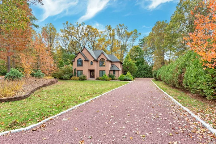 Set back on a gorgeous, lush two-acre property, this unique five-bedroom, three-full and two-half bath, brick Tudor may surprise you to know it was built in 2004. With many of the charming elements of houses built in the early Twentieth Century, it creates a warm and nostalgic ambiance with its steep gable and hip roof lines, its casement and arched windows, and an interior with richly stained moldings, wide-plank hardwood floors, spacious gathering places, superb custom artisan embellishments, and massive stone fireplaces - one elegant, one rustic, and one modern. Set far back from a cul-de-sac street serving a total of five luxury properties, it is conveniently located in the southeast corner of Old Westbury. Perfect for commuting to Manhattan via the nearby freeways and train station, it is close to premier shopping, dining, golf, mansion museums, equestrian trails, and renowned hospitals. Enjoying a sense of seclusion, this stately home enjoys a triangular property with a magical pristine woodland on one side and sweeping lawns edged by mature evergreens on the other. A long crushed-stone driveway provides access to an attached three-car garage tucked behind the home providing additional privacy to a spacious level lawn just waiting for you to add a pool and patio to your liking.
Impressive doors with circular leaded-glass insets welcome you into a grand, two-story entrance foyer featuring gleaming travertine floors, with inset medallion, richly stained millwork, and a graceful floating staircase ascending beneath a massive arched window to a second-floor balcony. To your right, next to a stunning glass-tile powder room, an elevator awaits to take you to second and basement floors. On the left, past a sunny study and guest closet, you will enter a spacious living room boasting hardwood floors, open-beam vaulted ceiling, and a massive stone fireplace reminiscent of an Adirondack lodge. With closet, plumbing for a wet bar, and French doors to the rear property, it creates a perfect space for entertaining. So does the extraordinary formal dining room that is entered from the rear of the foyer. Superb craftsmanship is exhibited in its Greek key inlaid hardwood floors and its elegant marble fireplace illuminated by a wall of windows and French doors opening to the rear property. The adjoining eat-in-kitchen is a cook’s delight featuring ample furniture-like cherry cabinetry with marble countertop, peninsula with seating, decorative tile and glass backsplash, under-cabinet lighting, and high-end stainless-steel appliances. Hardwood floors flow into the sunny breakfast area with French doors to the rear property and access to the attached three-car garage. Here, stairs descend to the full, finished basement.

From the sun-swept second floor balcony the palatial master suite includes an entry hall with access to two walk-in closets, and a spacious master bedroom boasting two dormered sitting nooks, a large arched window, a fireplace, and a luxury marble bath with steam shower, large whirlpool tub beneath an arched window, sitting area, and twin dresser vanity. This level also features a laundry room, a lovely bedroom with bath en suite and large closet, plus two additional bedrooms sharing a hall bath. One bedroom provides attic access. Boasting large sunny rooms, high ceilings, hardwood floors, and ensconced on two magnificent acres convenient to all the North Shore has to offer, this modern interpretation of an English Tudor invites you to let your imagination soar as you transform it into the home of your dreams. 