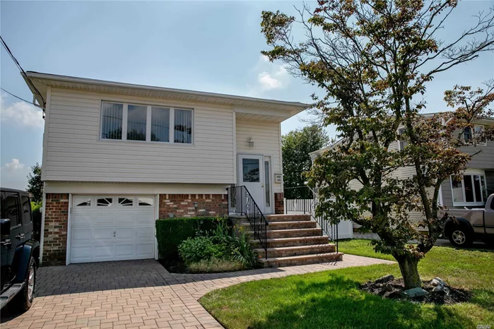 This spacious Hi-Ranch is perfect for extended family and is located within one mile of the LIRR. Upstairs level has beautiful hardwood floors, three bedrooms, full bath, , EIK, LR/DR. Lower level has a summer kitchen for entertaining with full bath, den and bedroom/office. Sliders to large deck on lower level provide access to large open backyard.Fully fenced property with double wide paver driveway and one car garage.