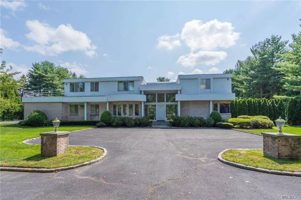 Beautiful Contemporary/Colonial with Brick/Stucco. Grand entry foyer with marble flooring, beautiful sunken formal living room with wood floors, and floor-to-ceiling windows overlooking the magnificent view of 2 flat acres of manicured land with a beautiful garden to the left of the inground pool and a wrap-around deck. On the right side of the entryway a large marble bar, a spacious den with wood burning fireplace fabulous for entertaining. To Left, of the entry is an eat-in chef&rsquo;s kitchen Wolf professional stainless steel appliances, a first-floor bedroom suite, with a full bath, a laundry room, and garage entrance, This home has 5 en-suite Bedrooms 6.5 Baths. Wheatley Schools.