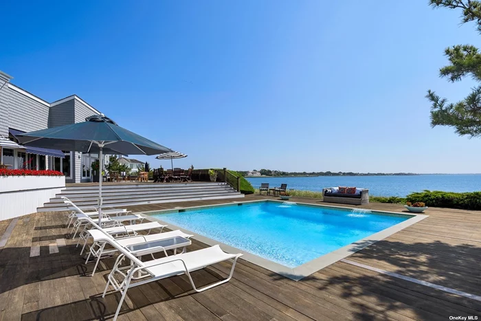 Serenity and privacy abound on this breathtaking bayfront property! Sited on +/- 0.82 acre, this 5-bedroom, 5.5-bathroom transitional home is surrounded by the sights and sounds of nature, +/- 238 feet of frontage on Moriches Bay, and access to an adjacent protected lagoon. The 25&rsquo;x25&rsquo; heated, gunite inground pool, one of the few square pools in the Hamptons, overlooks the open bay with both shallow and +/- 8&rsquo; deep ends, and a +/- 5&rsquo; standing ledge for soaking up the panoramic view. The expansive decking, covered cabana, and poolhouse with full bathroom and kitchenette offer multiple opportunities for entertaining or relaxing. Each of the 5 en-suites, with generously-sized first and second floor primary suites, provides a scenic water view. The cathedral ceiling of the open concept living/dining room provides an abundance of natural light, while the eat-in chef&rsquo;s kitchen includes a 6-burner Thermador range, double ovens, warming drawer, microwave, 2 Miele dishwashers, & center island.