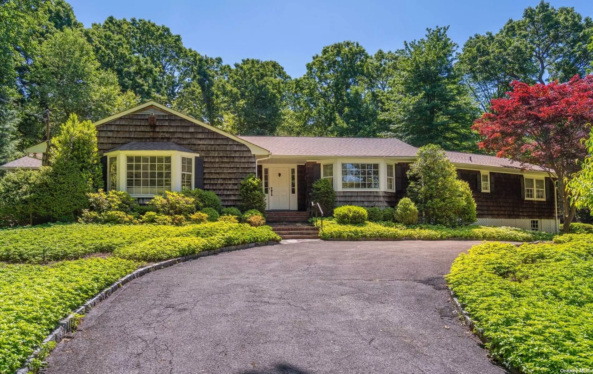 This country ranch is calling out to the buyer who enjoys lush botanical gardens. Center hall foyer with marble flooring introduces an elegant living room that has been detailed with custom built-in shelving, marble mantled fireplace and charming terrace. Enjoy entertaining family and friends for the holidays in a dramatic windowed dining room that overlooks the verdant front landscape. The hub of the home is the renovated chic white kitchen that highlights a center island, breakfast nook and is conveniently located within a few steps from the den. This room is casual and offers a spectacular view of the pool and two acres with access to the patio. There is a private primary wing with a generous bedroom and marble bath ensuite. Three additional bedrooms. Basement offers oversized recreation rooms. Locust Valley SD.