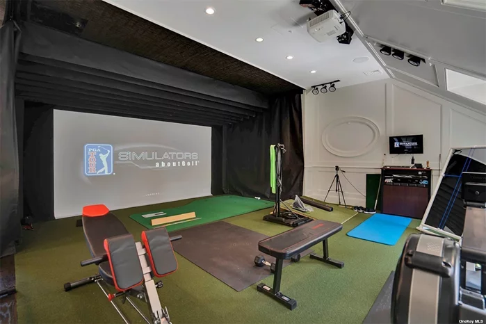 Upstairs large recreation room/exercise room featuring custom paneled walls, golf simulator and half bath