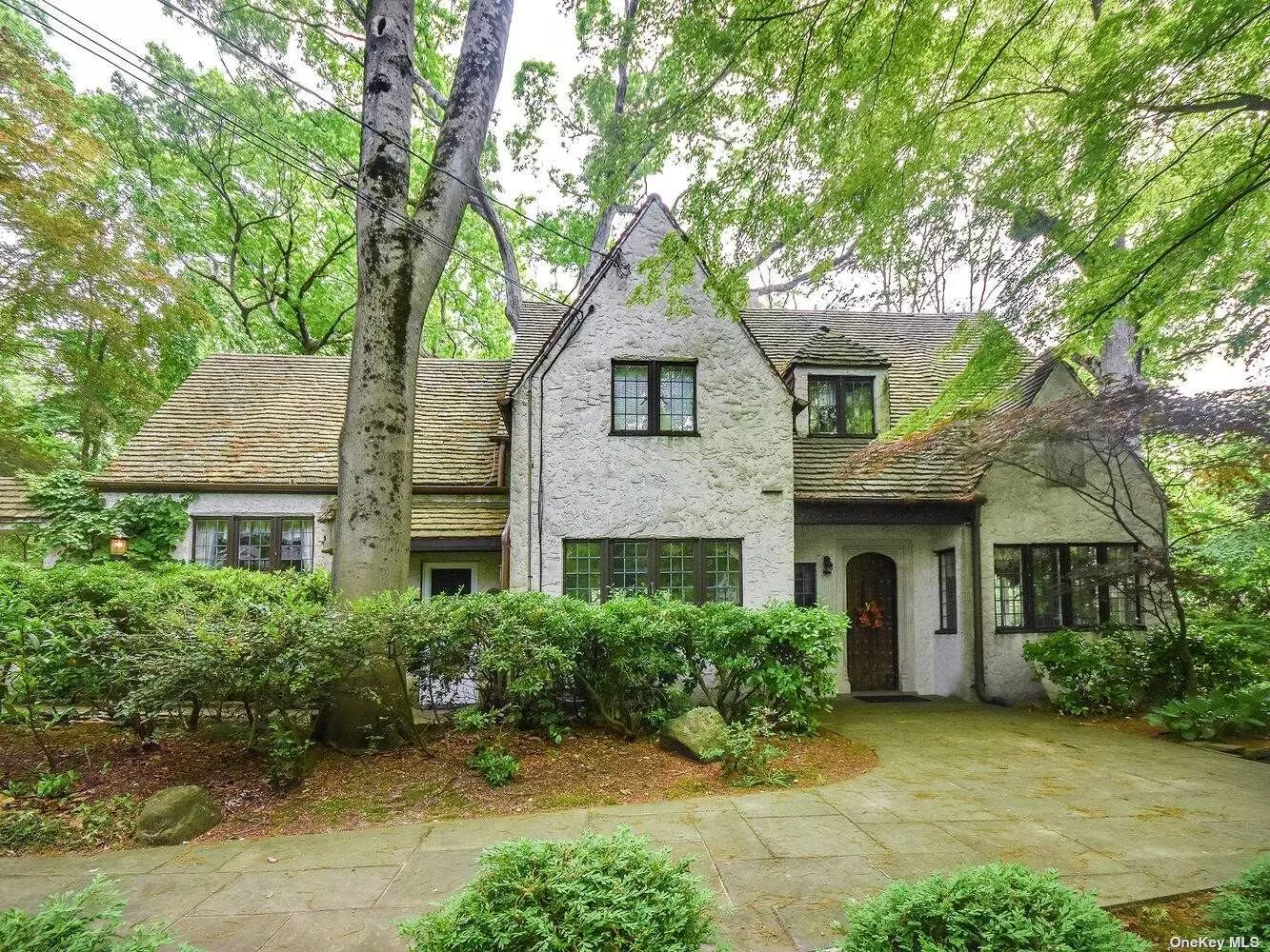Ever so charming 4 BR Traditional English Tudor nestled on lush private 1/2 acre steps to beach & schools. This home boasts a large Eat-in-Kitchen, sunlit Formal Dining Room, Living Room with fireplace, 1st floor Bedroom suite, summer screened in porch. The 2nd floor consists of a large Principal Suite plus 2 additional Bedrooms, 2 car garage, courtyard. North Shore Schools, beach privileges