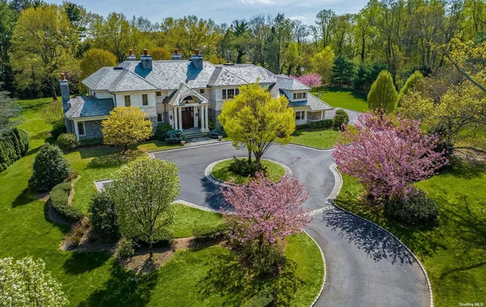 Willets Point Art Nouveau gates open to a long drive lined by evergreens and flowering trees that unfold to reveal this magnificent Estate. 12000+ SF on three levels combined, the home is a harmonious arrangement of hand cut limestone and field stone crowned with a Vermont Slate Roof. Mahogany doors open to an elegant two-story foyer. Transitional in style with unparalleled craftsmanship, four fireplaces, hardwood flooring, exotic stone, wainscoting and coffered high ceilings throughout. There is a handsome library/home office and living room with built in custom wet bar. A striking double -height den highlights custom cabinetry with a surround sound theater system and limestone fireplace that inspires relaxation and invites togetherness. Elegant dining can be enjoyed in the formal dining room. The first floor offers two-bedroom suites for long term guests. A thoughtfully designed chef&rsquo;s kitchen is adjacent to the den and has seating at the oversized island, custom walnut cabinetry and a sunlit informal breakfast nook. On the second floor, double doors open to a sumptuous primary en-suite with gas fireplace, sitting room, sublime marble bathroom and dressing rooms. There are four additional large bedrooms en-suite. The lower level boasts a temperature controlled 3000 bottle wine cellar, sports court, game room, yoga studio and fitness center. Landscaped gardens and travertine patios offer a haven for tranquility. Summer fun can be enjoyed by playing tennis, basketball or swimming in the sparkling salt water in-ground pool with hot tub. Three car-garage, Generator, Control4 Smart Home.