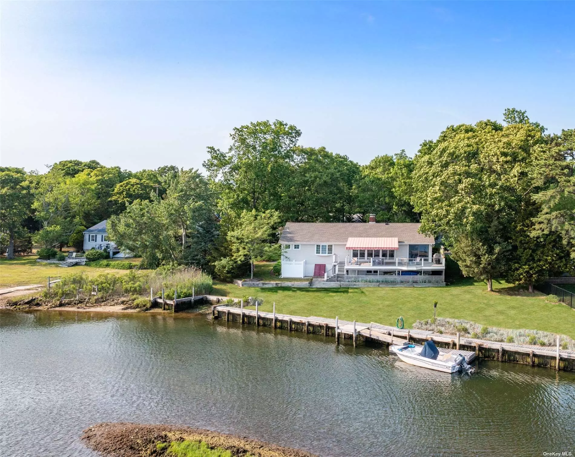 Waterfront ranch on James Creek with dock and large waterfront deck with shade- awning. Outdoor shower. Living room with fireplace and waterviews. Dining room with waterviews. Cozy den with TV. Master bedroom ensuite with waterviews - 3 Bedroom, 2 Bath in all. Walk to deeded bay beach. Close to Mattituck shopping, dining, Hampton Jitney and LI railroad. Work and play here!
