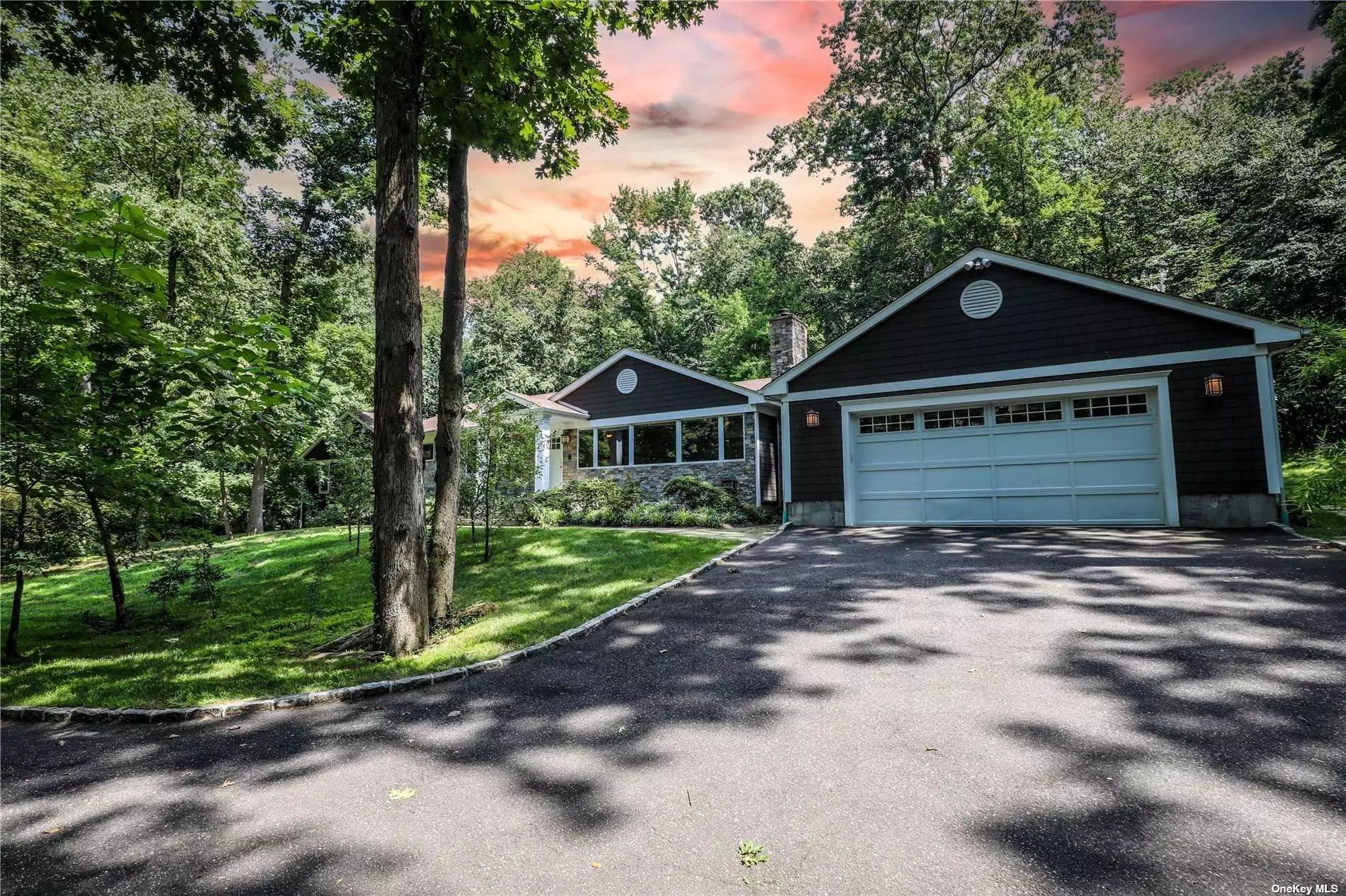 Brookville. Move-In Ready Modern Ranch located on a wooded 2-acre lot. Main level includes 5 bedrooms, 3 baths, a large mudroom/walk-in pantry off the 2-car garage entrance. The primary suite is encased by floor-to-ceiling windows with electric shades, its own enormous bathroom, and dual walk-in closets. The bathroom includes a soaking tub and stand-up shower, handheld shower head and body jets. The fully finished lower level includes the 6th bedroom, walk-in storage room and additional storage throughout, a laundry room with laundry chute from the main floor, full bath, and den/living area. The kitchen includes stainless steel appliances and an open concept to the dining area and living room, which also features a stone-faced fireplace.