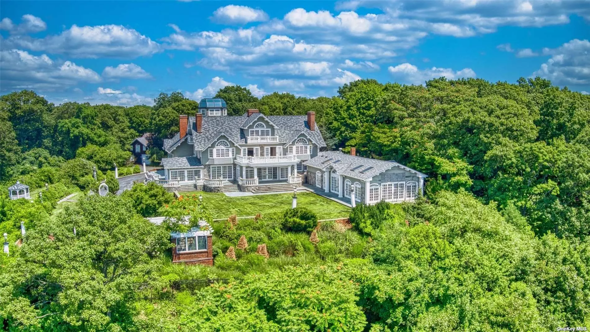 An Iconic and historic 10.9 acre Estate set proudly into the distinguished Waterfront Bluffs of Belle Terre. Serenity Estates, a composition of 7 Subdivided lots (9.5 Acres) and an additional 1.4 Acre premium Waterfront Subdivision make for one of North Shore Long Island&rsquo;s most remarkable purchase opportunities. 600&rsquo; of beachfront. 4 Waterfront and 4 Waterview Subdivisions in total. Elevated unobstructed and panoramic Sunset views of Port Jefferson Harbor, Pirates Cove and Long Island Sound. Existing 13, 800 Square foot Historic Waterfront Mansion constructed circa 1900. Gated entrance through fully lighted private Driveway into circular Auto Court and 3 Story Portes-Cocheres covered entrance. 5 Levels of Coastal luxury serviced by 3 Staircases and Elevator. Enter through oversized French Double Doors into a Sun-drenched Cathedral Foyer with Dual Sided Fireplace, Mezzanine Balcony and Side Hall Colonial Ballroom Staircase. Glass French Sliders span the Waterfront West Wall and provide egress to wraparound Blue Stone Deck and Courtyard. Chef&rsquo;s Kitchen with Dual Ranges, Dual Oven, Gas Fired Grill, Viking Professional Series Vented Hood, Oversized 6&rsquo;x24&rsquo; Center Island. Butler&rsquo;s Accessory Bar Room. Harbor-side panoramic Breakfast and Dining Rooms. Swimming Hall with 10 Person Spa and Lap Pool wrapped in Glass sliding French Doors. Mezzanine level includes Calacatta Marble Master Wing and Suite with Deck overlooking the Harbors. Dual Master Fireplaces. 2 Guest Bedrooms with Harbor-side Balconies and Fireplaces. Au Pair&rsquo;s Wing with separate entrance. 3rd story Lounge and Bar with Striking Center Chimney and Panoramic Harbor side Sunset views off Balcony. Accessory Guest Bedroom and Bath. 4th floor Widow&rsquo;s Peak and sweeping 360* domed Glass Observatory provide unrivaled views of the Harbor and Sunset. Finished Basement with Living, Media, Fitness, Sauna and Full Bathroom. 7 Bedroom, 5 Full Bathroom and 2 Half Bathroom. 22 Rooms in total. Granite Foundation, Apron and Retaining Walls. Composite Slate Roof equipped with Ice Cleats. Property features a 2, 650&rsquo; 2 Story Barn, 2, 250&rsquo; Stable and Workshop and an additional free standing 1, 650&rsquo; Cottage for Groundskeeper. Privately set deep off access road. Perfect for Equestrian Farm and Stable. Wonderful setting for Vineyard. Moments from Beaches, Golf Course, Country Club, Marina and all the amenities of Port Jefferson Village.