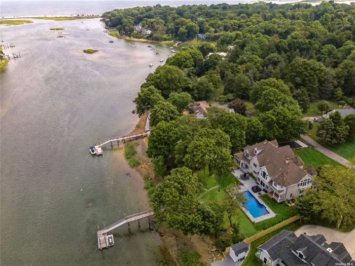 Nestled in the heart of historic Setauket, this Hamptons-style residence offers an unparalleled waterfront living experience. Poised on a serene and private lot with stunning water views on three sides, this exquisite property boasts a rare 160 feet of beachfront on Conscience Bay, making it a true waterfront oasis. This grand estate features six generously sized bedrooms, providing ample space. The primary suite is a haven of relaxation, complete with a luxurious en-suite adorned with upscale finishes and Kohler and Restoration Hardware fixtures, setting the stage for ultimate pampering. In addition to the primary en-suite, an additional two and a half well-appointed bathrooms cater to the comfort and convenience of all. Designed to meet the demands of modern living, this home features dual offices, ideal for those who seek a quiet and productive workspace. Rich hardwood floors grace the living areas, exuding elegance and warmth throughout the home. A double-sided fireplace adds an element of coziness, creating a perfect ambiance for gatherings and intimate moments. The gourmet chef&rsquo;s kitchen is a culinary masterpiece, equipped with top-of-the-line Thermador appliances and an oversized center island, providing ample room for meal preparation and casual dining. Perfect for hosting elaborate gatherings, the kitchen opens to a gracious dining area and offers seamless access to the outdoor screened porch. Step outside to discover your own private paradise, featuring an in-ground heated saltwater pool, where you can bask in the sun or take a refreshing swim with views of the sparkling bay. The meticulously landscaped grounds extend to a rare private dock, offering direct access to the shimmering waters, making this property a boater&rsquo;s dream. In addition to the beachfront, this property includes the rare benefit of deeded beach access, ensuring even more opportunities for seaside enjoyment. A private boat ramp provides convenient access for water activities, creating an idyllic waterfront lifestyle. Association dues for the deeded beach and boat ramp are $250/year. The timeless appeal of this residence is highlighted by its soaring two-story foyer and vaulted cathedral ceilings, creating an ambiance of grandeur and sophistication. The location provides a serene and peaceful environment, offering a sense of quiet retreat while still being in proximity to the rich historical charm of Setauket.