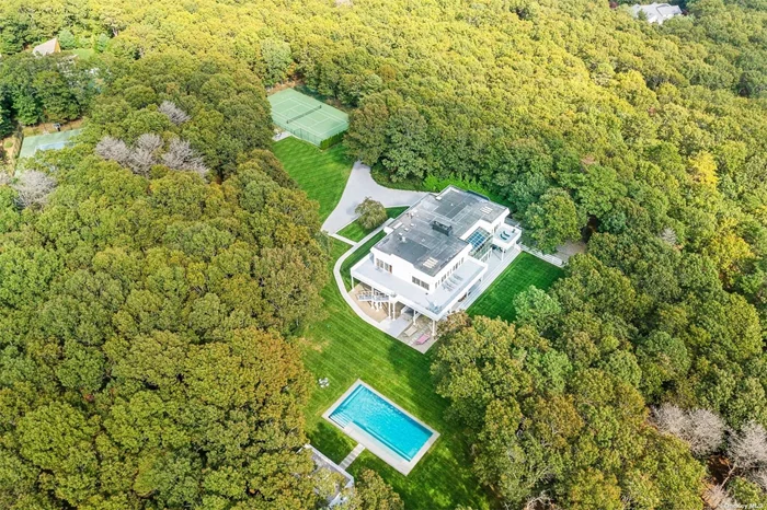 A winding private drive leads the way to Two Holes of Water Road. Along the way, you&rsquo;ll pass a full-size size North/south all-weather tennis court before arriving at the striking home&rsquo;s front steps. This uniquely situated estate enjoys seclusion and privacy while sitting just a short distance from the bustling village of East Hampton. The palatial 9, 000 square foot home features seven bedrooms and six and a half baths. The estate underwent a top-to-bottom renovation in 2019 and sits upon just under 11 sprawling acres. Marked by dramatic sculptural touches and wide expanses of scenic space, this property is made for the good life. A broad staircase in the spacious entry hall leads upstairs to an expansive 28&rsquo; x 35&rsquo; living room with a stately fireplace. This room opens up to an elegant formal dining room. Multiple exit points open up to a sweeping wrap-around 3000 feet deck 1st and second floor, that offers unparalleled property views. A fully outfitted kitchen features a generous pantry, wet bar and ice machine, double stoves, double dishwashers, and an outdoor Traeger grill. Four skylights bring in welcome light throughout the day. Custom cabinetry can be found not only in the commodious kitchen, but throughout the home. The large master bedroom boasts a fabulous bath, 3 steam showers on each floor, Toto toilet, and double doors leading out to a private deck. The main level features its own living room with fireplace and adjacent wet bar. A home made for entertaining, the estate features guest suites, two with direct access out to the immaculate backyard. An elevator connects all three floors and opens up to the large four-car garage. Lush lawn and green space surrounds the house and its sumptuous outdoor living space, which includes a 52&rsquo; heated Gunite pool. With all this, you can add a 1 mile walk path on the property so there&rsquo;s hardly a need to stray far from home, but when you do, high-end shopping, top-notch restaurants, and pristine ocean beaches await just minutes away in the nearby village.
