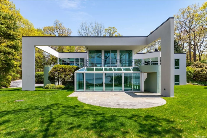 Perched on a cliff with breathtaking views of Oyster Bay on Long Island&rsquo;s North Shore, this extraordinary contemporary home is a masterpiece of modern architecture, nestled on just shy of four private waterfront acres in the prestigious Fort Hill enclave. The residence combines cutting-edge design with luxurious living, offering unparalleled elegance and sophistication. This cutting edge home, constructed of steel, concrete, and stucco, features an open plan that maximizes expansive vistas. Walls of glass and floor-to-ceiling windows flood the home with natural light, creating a seamless connection between the indoor and outdoor spaces and offering panoramic western water views and stunning sunsets. A central atrium links the upper arrival hall to a lower informal sitting area. The living room, surrounded by a wrap-around veranda, overlooks the coastline. The gourmet kitchen, equipped with top-of-the-line Miele appliances, features a sleek design and functional layout perfect for both everyday living and entertaining. An exterior patio connects the kitchen breakfast room to the lawn below. The lower level houses an indoor, sky-lit pool and spa, featuring a shower, Japanese soaking tub, and jacuzzi, providing a private oasis for relaxation. Guest bedroom suites open onto a private cliffside lawn. The property boasts waterfront access with a private beach, offering an exclusive and serene coastal lifestyle. Eco-friendly features like solar panels ensure energy efficiency and sustainability. Expansive wrap-around terraces offer stunning vistas and ample space for outdoor gatherings, while the protected nursery is perfect for gardening enthusiasts. The wine storage area accommodates a collection of fine wines. Ample parking is provided by the three-car heated garage, ensuring convenience and storage. This remarkable property combines modern architecture with luxurious amenities, just an hour from Manhattan. Experience the ultimate in contemporary living and embrace the privilege of private waterfront living with incredible sunsets, a private beach, and unparalleled elegance.