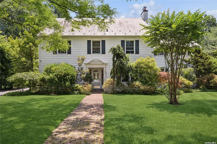 Nestled in an over a half-acre lot in the heart of East Williston, this impeccably maintained Colonial home features perfect landscaping, a distinctive slate roof, and a stunning brick porch with a stained glass enhanced door that adds to its classic charm. Once inside, you&rsquo;ll delight in the stunning ornamental woodwork from the arched doorways, to the crown moldings, and original built-ins. Gleaming hardwood floors flow throughout the home. The spacious layout starts with a formal dining room that comfortably fits 10 or more people! A massive adjoining kitchen includes a granite-topped island with a sink for easy prep work and informal snacking. Stainless steel appliances include a gas range and chef&rsquo;s quality hood. Tile flooring, recessed lighting, vast cabinetry with granite counters, and a nearby half-bath complete the kitchen. A glorious breakfast room follows, with double French doors for easy access to the expansive stone patio that doubles your entertainment space with a full outdoor kitchen with all the amenities. An old-fashioned screened-in porch/sunroom. The sunroom offers entrance to the formal living room via French doors. Hosting a brick fireplace with a sophisticated white mantel, this room provides a place to quiet one&rsquo;s mind after a long day. The adjoining den boasts wood paneling, boxed-in beams, built-in bookshelves, and a lovely brick fireplace. The sleeping level holds five bedrooms, each offering ample closet space and unique character. The primary suite includes a large walk-in closet and a spa-like private bath with a double vanity, ensuring a serene retreat after a long day. Two additional full bathrooms complete this level. The finished lower level can become anything your needs require: a home theatre, a home office, art studio, dance studio, crafting nook - your only restriction is your imagination! A laundry room with a washer and dryer, the home&rsquo;s mechanicals, and three large storage rooms finish this level. Some of the home&rsquo;s don&rsquo;t-miss features: a beautifully landscaped park-like private backyard complete with in-ground sprinklers, solar panels discretely located on the back of the home, a detached two-car garage, a walkup attic, near public transit, and local parks. This property offers a rare blend of vintage elegance and modern updates, making it a true standout in the neighborhood.