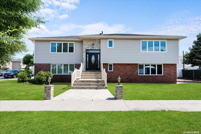 A rare Wide Line Hi Ranch, set up for a multi-generational lifestyle, is situated on an oversized corner lot in the desirable Rockwood Park area of Howard Beach. This property features a granite walkway and a ledger stone staircase, offering an elegant entrance.The first-floor walk-in level boasts a private outside entrance with exquisite chocolate wood grain porcelain tile flooring. This level includes a bonus room that can be used as a den or an extra bedroom. The primary bedroom on this floor has ample closet space. A separate full bath featuring luxurious stone tile and a Toto toilet. The remodeled and never used first floor area showcases light coffee cabinetry complemented by granite countertops and a separate island, creating a relaxed dining ambiance. It includes a 30-inch French door refrigerator with filtered water and ice, and a Kenmore microwave. There is also separate access to a utility room with a washer and dryer. The living area features sliding doors that reveal an open yard, which can be fenced in for privacy. Ascending to the upper level, you are greeted by a new leaded glass front door with transom and sidelights, slate flooring accentuated by oak wood banisters, and all new two-panel interior doors. The new 3/4 plywood subfloor with 4-inch-wide oak wood floors extends throughout the upper level. The newly renovated kitchen boasts granite countertops, cherry cabinetry, a slate backsplash, and stainless-steel appliances by Whirlpool Gold, including a 36-inch French door refrigerator with filtered water and ice, a double wall oven, a Blanco sink with a kitchen spray head, dishwasher, and microwave. This level includes 3 bedrooms. The primary bedroom features an ensuite bath complete with custom shower doors, Hansgrohe fixtures, a Toto toilet, natural stone accents, a custom vanity with a granite countertop, and a single sink. Additionally, the primary bedroom houses a convenient laundry hook-up for a stackable washer and dryer. The other two large bedrooms are complete with ample closet space. To finish out the floor plan there is the custom full hallway bathroom Rounding out the property&rsquo;s offerings are a private driveway, an attached 1-car garage with remote access, central air for climate control, forced air heating, a gas stand-alone hot water system, a robust 200-amp service, an electrical system that is a mere 8 years old, new sheetrock and high hats, triple-pane windows with lifetime transferable warranty, and a 40-year architectural roof.