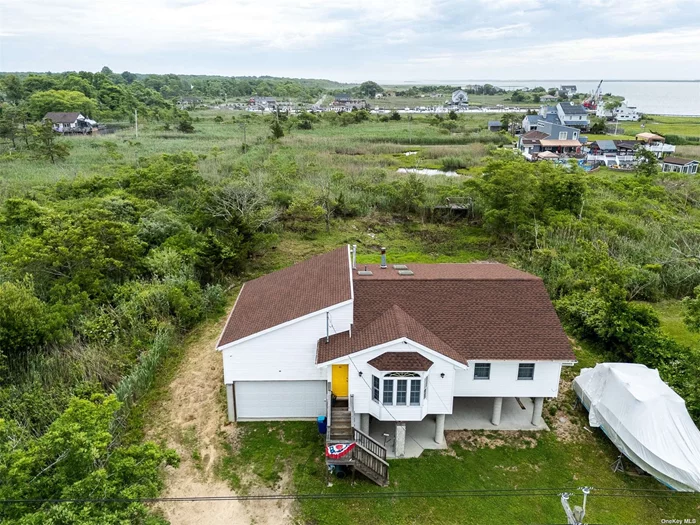 Welcome to 63 Beaver Drive in beautiful Mastic Beach. A stunning, one-of a kind custom built home Anchored upon 18 Solid concrete Columns. (Helical-pilings) Each support column goes down 12 feet underground insuring rock-solid stability and Strength. This entire home was lovingly restored /rebuilt in 2022, Sparing No expense. Restoration includes New roof, New hardwood floors New sub-flooring / joists, All new electrical and plumbing throughout house new A/c unit new furnace with sealed (anti freeze) base board heating System, New hot water heater. All new septic system with 1, 500 gal main tank and 5 overflows, each installed 1.5&rsquo;above grade, then had property back-filled. New gas-lines with 3 100 gal. propane tanks on regulation cement-pad. There is a 16 Thick concrete slab under house with 7.5&rsquo; of clearance. The underside of the home&rsquo;s floor is fully insulated and enclosed. All exterior wall of this home were framed with 2x8 (double thick) and are all double insulated. Home has security cameras on all sides for peace of mind. Inside the entry foyer opens into a large living room with beautiful Anderson bay windows with overlooks serene woodlands. Watch magnificent sunsets. The new bathroom is huge with high cathedral, ceiling skylight, new walk-in shower with frameless glass door and built in granite shower seat there is a laundry nook off bathroom with stackable washer, dryer and entry door into very large two story high attached two car garage. The grand room offers an impressive 14 foot high wood plank cathedral ceiling with two skylights three sets of beautiful Anderson double pained wood sliders With overhead elliptical windows open to the room 13 x 36 wrap around raised deck that overlooks your huge 100 x 200 property and offers magnificent panoramic views of the great south bay and fire Island enjoying your favorite cocktail while breathing the salt air and watching the boats go by. House is currently a one bedroom however there is approximately 700 ft.? of renovation space above the large two-story high garage. no exterior extension will be needed to add living space kitchen is also new with beautiful redwood cabinets, granite countertop and stone backsplash this home has been loved and well cared for by same owner for 54 years and it shows unique opportunity home also being offered fully furnished.