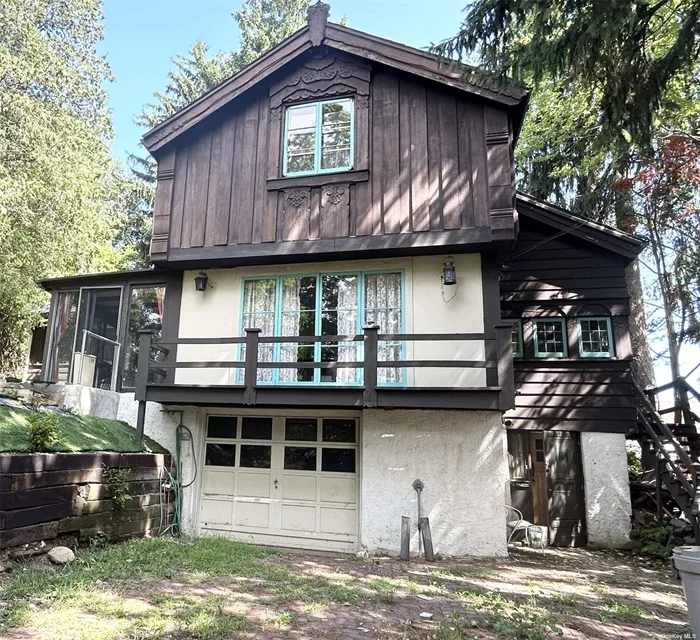 Looking for something different in Douglas Manor!  This property is one of the most unusual in the neighborhood and is known as The Chalet. This is probably one of the most unique Arts and Crafts houses in the historic section of Douglas Manor built by Norwegian decorative artist, Trygve Hammer. His work includes the bas-relief sculptures that adorned the old Bonwitt Teller facade on Fifth Avenue and the Waldorff Astoria Hotel dining room. Hammer and his wife emigrated to New York in 1902 and built the first part of the house, the story and half high living room in 1916. In 1922 the Hammer&rsquo;s expanded it to its current configuration adding the three bedrooms on a second story. The allusion to the mountain chalet is no accident. Hammer modeled his design on a stue, a 17th century farmhouse style indigenous to Setesdal, Norway. Upon entering the front door you&rsquo;ll find an eat-in kitchen with hand crafted cabinets on the right side with a half bathroom to your left. Walking straight ahead you enter a unique parlor with French doors that lead to a balcony overlooking the garden.  To your right you&rsquo;ll find a pair of matching doors that Hammer painted in 1926 in rosemaling, a type of colorful Norwegian folk painting. There&rsquo;s a cozy sitting room with a wood burning fireplace off the parlor which leads to a formal dining room with a door that leads to the backyard. Take three steps up and you enter the very large living room, which was Hammer&rsquo;s original studio. Soaring ceilings with timbers, a large window, a skylight and a large wood burning fireplace finishes off this great entertainment space. There is also a full bathroom off the living room. At the top of the steps on the second floor to your left you&rsquo;ll find the main bedroom with a cathedral ceiling, a large window overlooking the garden and built-in shelving. There are two other bedrooms and a full bath on the second floor. There are plenty of closets and unique storage spaces throughout the rooms. Walking through the house you&rsquo;ll see Hammer&rsquo;s stained-glass windows and many of his Arts and Crafts touches in the rooms. The basement features a studio apartment with a kitchenette and full bathroom. There&rsquo;s also a one-car garage with a large storage room next to it. Hammer surrounded the house with seven Norway spruces to remind him of his native country. The exterior includes darkly stained board and batten siding, a copper roof over the studio and a slate roof over the rest of the house. The focal point of the house is hand carved bargeboards that accent the roofline and vertical corners at the main gable, and the carved decoration at the peak of the house. The house has steam heating and central air conditioning. Over the studio are of the house is copper roofing with slate covering the rest of the house. The Chalet has only had three owners with the current owner purchasing it in 1955. The previous owner was famed commercial illustrator, Earl Oliver. SOLD AS IS