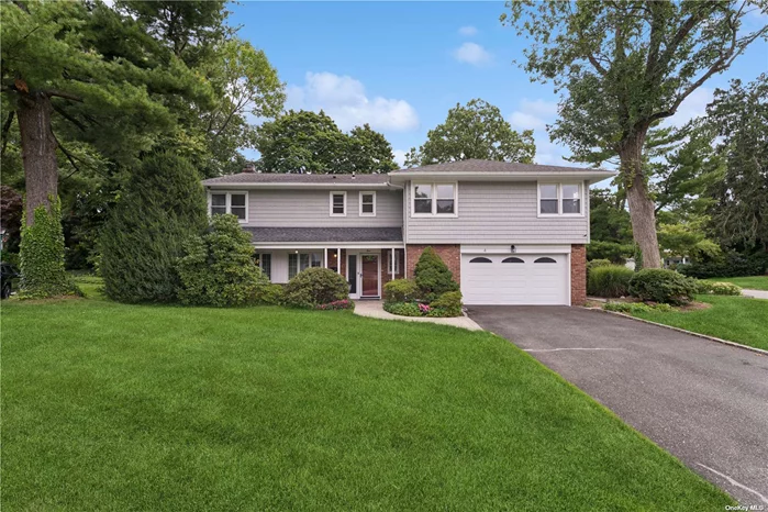 This stunning front to back split-level home with four bedrooms and 2.5 bathrooms on a cul de sac is within walking distance to buses and the LIRR. The newly sided and updated exterior of this home features an insulated garage door and new gutters with the Leaf Filter system. This home has a private driveway and walkway to a tiled foyer which opens onto your family room with a fireplace and wet bar. Also accessible from the foyer is a half bathroom and an entrance to your laundry/mud room. The laundry room features a washer and a dryer, plenty of counter and storage space, and a second refrigerator. Walking up a half flight of stairs leads you to the bright Living Room/Dining Room with a cathedral ceiling. This great room concept has a bank of large windows and glass doors leading to your oversized slate patio. The Eat-in Kitchen has Cherrywood Cabinets with a new stainless-steel refrigerator and microwave.  The staircase that features stained oak handrails leads to the second-floor open landing with a walk-in storage closet and oversized linen closet. The large master bedroom features an office nook area, two walk-in closets and an ensuite bathroom. The large second bathroom features a make-up area, dual sinks and a whirlpool tub. Of the three other bedrooms one large bedroom has a walk-in closet, another large bedroom has sliding mirror closet doors with a built-in dresser and the third bedroom (which was used as a second office area) has a sliding door closet. The partially finished basement has lots of storage plus a Gas furnace and standalone water heater. The oversized garage has ample storage areas, cabinets and work area. This picturesque home sits on a 0.2599-acre lot with a tree lined back yard. Plus, the sale also includes a separate unimproved 0.0718-acre wooded lot, for a total of 0.3317 acres for the entire property.  A property tax grievance is on file for 2024/25.