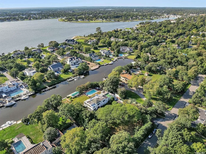 This Mediterranean-style home, built in 1898, sits on a spacious 150-by-316-foot property, blending European inspiration with the charm of a waterfront retreat. With six bedrooms, three full bathrooms, and two half-bathrooms spread across three stories, the house is ideal for both family living and entertaining. The second-floor master suite is a standout, featuring a cozy fireplace and a veranda that overlooks a deepwater canal, perfect for enjoying serene views. The exterior, characterized by its stucco and concrete construction, nods to the Mediterranean style that was a rarity in America at the time. The property includes an inviting inground pool and a canal-facing boathouse topped with a classic Spanish-style roof, providing ample space for a 60- or 70-foot boat. Designed as part of Bayberry Point, a historic summertime destination developed by the Havemeyer family, the home offers a blend of luxury and timeless elegance in a tranquil setting.