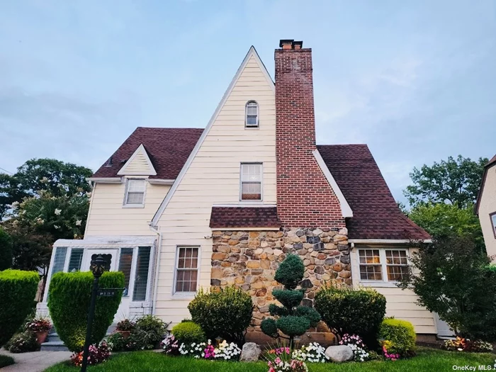 Situated in the coveted Addisleigh Park Historic District, this elegant Tudor-style home combines historic charm with modern comforts. Set on a generous 60x100 lot, the property offers 5 bedrooms, 2.5 bathrooms, additional pluming on 3rd floor for bathroom if needed and a separate office. The home features an eat-in-kitchen, extra-large formal dining room, perfect for hosting large gatherings, a living room with a gas fireplace, and a fully finished basement. Beautiful hardwood flooring runs throughout, while the living and dining rooms are accented with crown molding. The eat-in kitchen is equipped with stainless steel appliances and granite countertops. The finished basement provides a versatile space with egress to the beautifully landscaped backyard, which is perfect for outdoor entertaining with its Trex deck and paver patio. There is a private driveway leading to a detached two-car garage with a pull-down ladder for attic storage. Public transportation is just a few blocks away, with easy access to the Q4 bus line and St. Albans LIRR station. Too much to list!