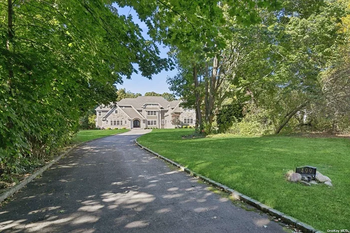 Built in 2017, this magnificent stone and shingle Colonial home is perfectly situated on 2.56 acres on a quiet, tree-lined street. Welcoming double-entry doors open to a beautiful foyer with crisp white millwork and a soaring ceiling. Featuring a bright and airy open floor plan, this incredible home boasts a great room with a 2-story ceiling and floor-to-ceiling windows flanking a beautiful brick fireplace as well as a spacious dining room with a coffered ceiling and field-panel wainscot. The stunning kitchen is open to the living and dining areas and outfitted with custom cabinetry, quartz counters, high-end appliances, ample storage, a large center island with seating, and a lovely breakfast area. The serene master suite is located on the main floor and offers an expansive bedroom with a tiered-tray ceiling, access to the exterior, generous walk-in closets, and a luxurious marble master bath with dual vanities, shower for two, and a charming claw-foot tub. There is an en-suite guest room on the main floor with 4 additional en-suite bedrooms on the 2nd floor that all feature ample closet space and tastefully appointed bathrooms with designer fixtures and fittings. Outdoors, the manicured property has a patio, mature plantings, professional landscaping, and plenty of room for a pool. Property highlights include a huge bonus room ideal as a home office or gym, 7-zone indoor/outdoor built-in Sonos speaker system, millwork with exquisite architectural details and gorgeous hardwood floors throughout, a laundry room with a sink, central-vac, 4-zone HVAC, security system, and a 3-car garage. Conveniently located to all parkways, shopping, dining, and only 2.1 miles from the LIRR. Complete with mooring rights and just minutes to the Laurel Hollow residents beach, this phenomenal property represents Gold Coast luxury living at its finest.