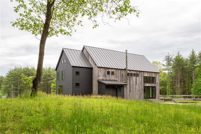 A long winding country road, a dirt driveway, a fifty acre sanctuary. This stunning post & beam barn house sits on a one acre pond amid fields & fields of wildflowers and deep pine forest. Built by a premier builder in the area, the contemporary home has 20ft ceilings, a giant expanse that feels warm and inviting. The home is longer than it is wide with a substantial kitchen at the center. A large island and dining table run side by side, and you&rsquo;ll find high end appliances in a sharp, polished black finish. A wood burning stove sits between the kitchen and living room, and a den sits in the northwest corner. This entire first floor looks out over the pond to the fields in the distance. Upstairs, you have a giant open loft overlooking the main living space, a bedroom with gorgeous views of the property and a full bath. Antique fixtures such as faucets, sinks and hardware are interspersed throughout the home, and the post and beam construction incorporates reclaimed hand hewn beams, making this new build feel authentic and well beyond its years (in a good way). Radiant heated concrete floors span the lower level of the home where you&rsquo;ll find three bedrooms. Two share a full bath, and one is ensuite with a large, walk-in closet and glass doors leading outside to a pebble patio overlooking the water. There is also a sitting room on the lower level, light and bright, with sliding glass doors that lead outside. The entire house is west facing and enjoys fabulous sunsets. A cottage is tucked back against the tree line, as charming as could possibly be with a full kitchen, a large bedroom and a full bath. 2.5h to NYC, 2.5h to Boston, 30m to Hudson and Amtrak. Dorland Farm is a little slice of Hudson Valley heaven.