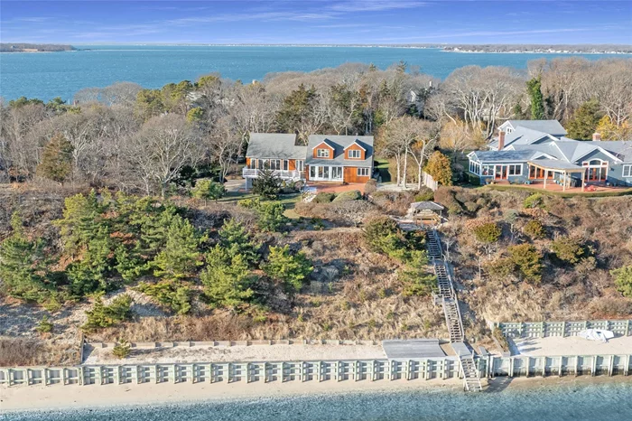 Perched high above the water on sought-after Nassau Point, this exceptional 4-bedroom, 2-bath home offers breathtaking views overlooking Peconic Bay. Enclosed in glass on the East and South sides, the home is bathed in natural light, providing the perfect vantage point to enjoy both sunrises and sunsets. The open floor plan seamlessly integrates the living and dining areas, creating a warm and inviting space for gatherings. A vaulted ceiling with stunning exposed beams enhances the spaciousness, adding architectural charm and character. The thoughtfully designed layout is ideal for both relaxation and entertaining. Outside, a large deck and two expansive patios offer wonderful spaces for outdoor dining and lounging, with plenty of room to entertain guests or simply soak in the serene surroundings. At the top of the bluff, a permanent gazebo with comfortable seating provides a tranquil spot to take in panoramic views of Southampton and Jessup Neck. Private stairs lead down to 142ft of pristine shoreline, complete with a sandy sun platform, perfect for beach days and enjoying the water, all protected by a sturdy bulkhead.This property truly captures the essence of North Fork living, combining stunning natural beauty with elegant design and the promise of endless waterfront enjoyment.