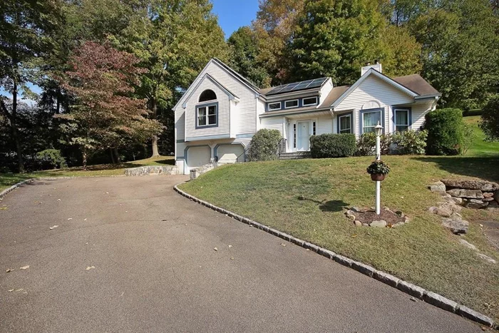 Terrific front to back split at the of a cul-de-sac! Wonderfully, private setting with lots of updates and picturesque rear patio with freshwater salt system hot tub & decking surround. Many updates include updated windows, boiler, hot water heater, central air, and fabulous primary bath. Enjoy the marble fireplace in the living room with cathedral ceiling, hardwood floors, double walk in closets in primary bedroom & spacious finished lower level. Solar paneled roof (pre-paid) drastically reduces monthly electric bills! Convenient above ground oil tank and outlets for charging EV vehicles. This is an environmentally friendly home!