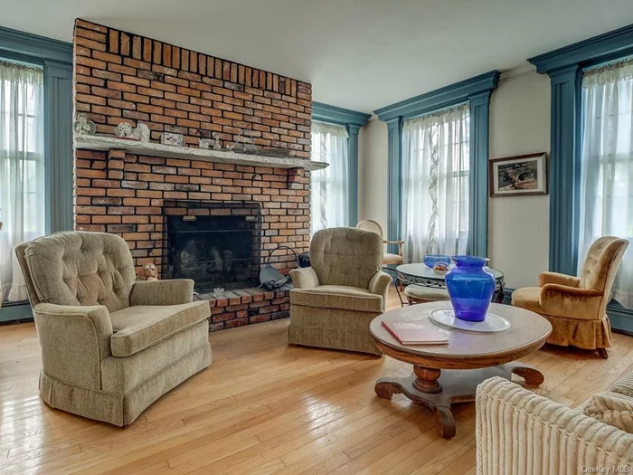 Front living room has full length windows with wide colonial moldings and hardwood floors. Brick wood burning fireplace is one of three in this lovely home.