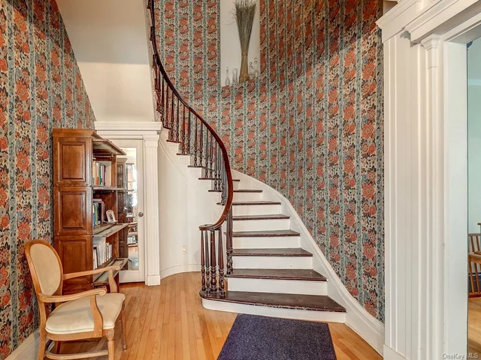 Wide formal entry with gorgeous mahogany railed curved staircase. Take note of the beautiful molding as well. To the right is one of the two formal living rooms.