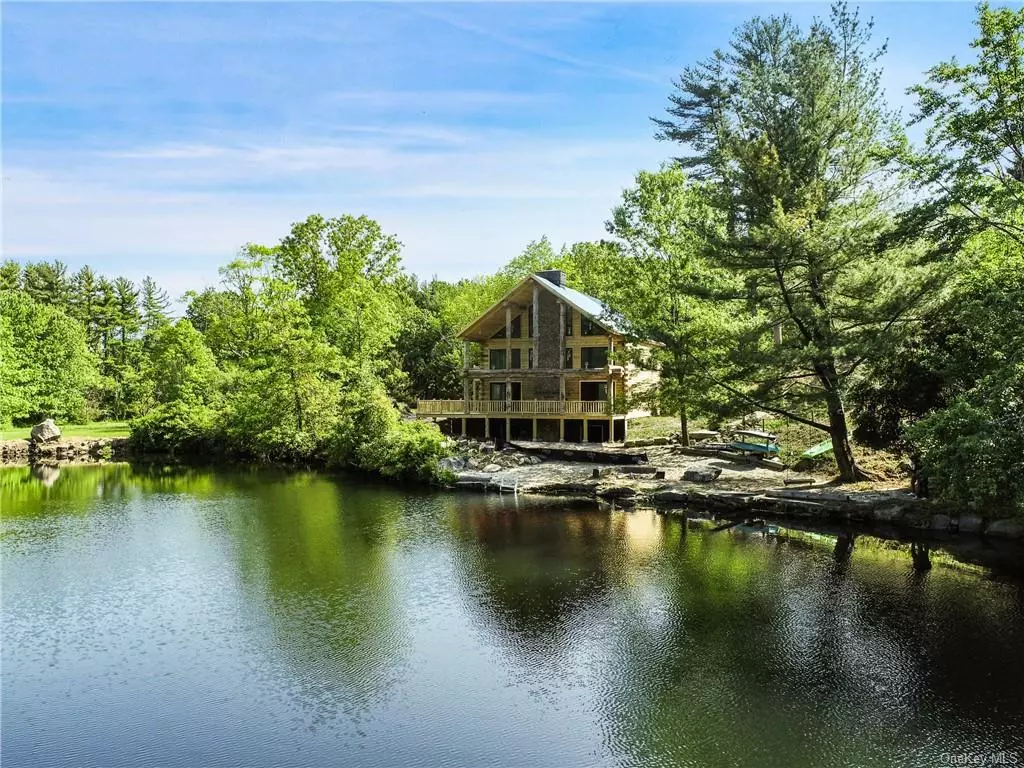 Modern waterfront Log Cabin sanctuary steps away from your own sandy beach on Quarry Lake, a pristine, deep, spring-fed lake. This breathtaking ground up, new build offers a Great Room with a soaring two-story stone fireplace framed with floor-to-ceiling windows which gaze at nothing but majestic water views. A custom kitchen, ensuite bedroom and powder room are also located on the main floor. The secluded primary suite encompasses the upper level, enhanced with its wraparound outdoor terrace. A finished lower level incorporates the playroom, laundry and a half bath. This nature enthusiast&rsquo;s paradise, on nearly 8 acres, offers amenities which include fishing, boating, swimming, and walking trails around the property. Three additional structures remain which include the original home and two outbuildings. Minutes to the airport, shopping and train station. Just a 40 min commute to NYC. Log cabin is approximately 65% complete.