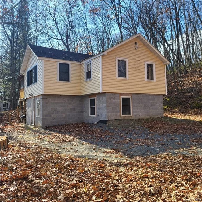 Looking for a cozy and charming home in Wurtsboro, NY? Look no further than this 2 level, 1720 sq. ft. 2 bed/2 bath home that offers you the best of both worlds: privacy and convenience. The lower level has its own entrance and a staircase leading to the second floor. There is a mud room, bathroom, utility area and 2 rooms that can be used as extra bedrooms, a laundry room or office space. The second floor has wood floors throughout, a den area with great views, a living room with a wood burning fireplace, and an indoor porch adjoined to the kitchen that can be used as a dining space. The property has 2 levels, is lined with stone walls and has a driveway and and a parking lot that can fit approximately 6 cars. This home has been recently renovated with new windows, walls in lower level, foundation,  floor, bathroom, eco-friendly efficient well tank, electric wiring, outlets and switches. Some cosmetic work needs to be finished. With a little TLC this home can shine. Low taxes.