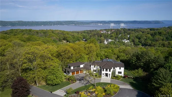 On top of a hill with a spectacular view of the Hudson River and the new Mario Cuomo Bridge, nestled on a tranquil cul-de-sac, this contemporary home offers a harmonious blend of living and office/work space luxury. LIVING SPACE: past the foyer and the entrance hall lie the open floor plan living and dining areas with majestic windows and views day and night, an ideal setting for home life and entertainment. A media room abuts the spacious entrance hall. The modern kitchen features German custom cabinetry and appliances, a center island and breakfast area that serve as focal points for culinary creations and social gatherings. The upstairs master suite with its large windows, a luxurious en-suite bathroom, a boudoir and two walk-in closets offer ultimate comfort and relaxation. Additional 4 bedrooms and well-appointed bathrooms ensure ample space for loved ones and guests. The outdoor oasis includes covered living and dining areas with a built-in Lynx BBQ plus an expansive patio leading to the heated salt water pool. The lower level provides two large plus several smaller storage areas, a gym and a gallery for hanging art. OFFICE/WORK SPACE: with its separate entrance leading to the main floor office plus bathroom and to a second floor large office with ample storage. Both offices can be converted to additional bedrooms. Designed and built for/by the art collector/developer/owner there is an elevator, radiant heat flooring, Lutron smart home system, ceiling speakers and a three-car garage pre wired for EVs.