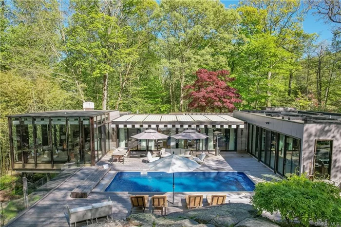 Introducing this stunning mid-century modern retreat, nestled in the serene woods in Scarsdale School District. Step into another world as you arrive at this magical home surrounded by trees and a picturesque creek, offering breathtaking views through its floor-to-ceiling windows. This architectural masterpiece embodies the essence of a vacation lifestyle everyday. The captivating living spaces with gorgeous architectural details wrap around a private deck and pool, making every day feel like a resort-style escape. The home boasts six bedrooms, all with custom outfitted closets, 4.5 baths and offers a seamless blend of modern luxury and timeless design throughout. This remarkable property offers a rare opportunity to enjoy a private, wooded oasis while being just moments away from the train and town.