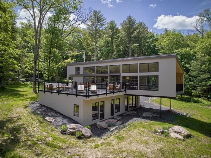 Bathed in calm whites and neutrals, this designer-built waterfront home delivers a masterclass on organic luxury. Tucked into the pines of the Black Forest Club and just 90 miles to NYC. This architectural gem&rsquo;s cantilevered shape, modern and elevated, sits in a verdant clearing surrounded by wildflowers and artful rock gardens. A modern, stucco facade sets a soothing stage as you enter the home. The open plan main level is surrounded by walls of windows and soaring ceilings. The sunny living space is anchored by an efficient, wood burning stove, before flowing into a generous dining area with access to an expansive sundeck that wraps around to the front of the house. The chef&rsquo;s kitchen features Bertazzoni appliances, high end custom Italian cabinetry and natural quartzite countertops. The lower level houses three airy bedrooms, each with private access to the grounds. The en suite bathroom leans spa-like, with its soak tub and textures, while the second shared bathroom evokes a similar sentiment. The reading nook feels hand-carved out of the hallway tying each room together. Design elements throughout the home include limewash walls and plaster finishes, built-in shelving and rounded bullnose edges. The custom Italian cabinetry and high end German window package lend a sense of precision and poise. At the risk of overusing the word custom, we can&rsquo;t emphasize enough the degree to which Whispering Pines is truly a handcrafted home. Built in 2024, the home&rsquo;s envelope features DIFS stucco siding and a standing seam metal roof. Design aficionados will recognize the complex architecture and engineering - a shape that began as a hand drawn idea and over many months became a reality. The indoor-outdoor connection is real, and you choose the degree to which you want to experience it. A 700 square foot sundeck, and a second, smaller but private deck, extend off of the main living space. Beautiful rock gardens are dotted around each exterior door, and a few steps further lead you to an oversized fire pit. Adirondack chairs perched on the hillside direct you further down to the riverfront, audible from the home and swimmable in summer months. For further adventuring, Whispering Pines is part of the Black Forest Club, a sought after private community offering residents exclusive access to 1, 100 acres of mapped hiking trails, swimming holes, stunning ravines, fishing, and four-season fun.