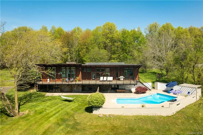 This incredible mid-century gem perfectly marries elevated architectural design and day-to-day functionality. Featuring mountain views, a dreamy pool and easy commute into NYC, this special spot is a rare find and ideal retreat! The butterfly style roof allows each wing of this special home to have vaulted ceilings with impressive exposed beams and oversized windows that create a fully immersive experience with nature. The mountain views provide a scenic backdrop to enjoy through all four seasons. A central wall divides the kitchen and dining space from the living room while still feeling open and connected. The fireplace provides a warm and cozy atmosphere during the cooler months. Oversized doors blend seamlessly with the wall of windows and lead out to the wrap around deck even further blurring the line between inside and out. The home thoughtfully separates living and sleeping spaces with all 4 bedrooms peacefully tucked away. Each room has high ceilings, floor-to-ceiling windows, and ample closet space. The primary suite is grand in proportion and has a stunning en suite with a private sauna, soaking tub, and more of those majestic scenic views. With the mountains never out of sight, the outside spaces of this home are just as spectacular. A magnificent south-facing deck spans the entire length of the home. Perfect for afternoons with a book or dining al fresco, this spacious area also leads right down to the inground pool. It&rsquo;s easy to imagine perfect days swimming and sunning with family and friends in this perfect summer oasis. A large sports court awaits your vision and would be perfect for pickleball, tennis or basketball. In the heart of the Black Dirt Region famed for its charming independent farms, this home is conveniently located near many cute towns for shopping and dining like Warwick and Port Jervis (which has a MetroNorth stop). A wide variety of orchards, vineyards, and craft breweries can be found 10-20 minutes away and you are only 20-30 mins to ski resorts, the Appalachian Trail, and many state parks and forests for hiking and skiing. There is so much fun to be had on the nearby Delaware River with canoeing, kayaking, and rafting in the warmer months! Venture a bit further and discover great dining, shopping and arts/entertainment in Newburgh and Beacon. There are multiple options for public transportation to/from NYC and you are only 65 miles to the GWB!