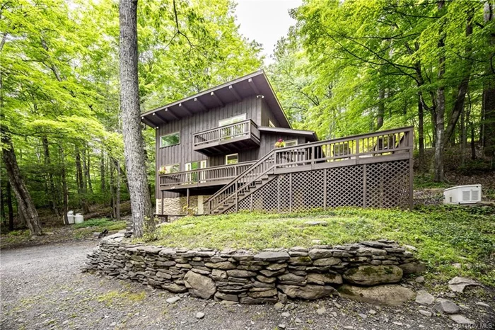 Enjoy the peace and beauty of the woods from this beautifully situated, recently renovated contemporary located in Willow between Woodstock and Phoenicia. Set on 3.55 secluded acres, this soaring two-bedroom, two-bath home with a stellar bonus room offers seasonal mountain views and membership to a community swimming pond. Imagine driving through the forest to an elegant modern retreat with abundant light and plenty of outdoor spaces for unwinding and entertaining. In addition to the 679-square-foot wraparound deck, there are balconies off each bedroom from which to enjoy nature while sipping a beverage or relaxing with a book. Inside the home, the open-plan kitchen/dining area with full bath leads to a dramatic living room featuring a cathedral ceiling and attractive stone fireplace. The forest views are stunning. Stairs lead to the primary bedroom, a bonus room, and a generous bathroom with walk-in shower and deep soaking tub. In the bedroom, light pours in from a skylight. Sliders lead to a private balcony. The north-facing bonus room, with its bank of windows, might make a great studio, office, or den. (It is large enough for a desk and couches or a queen-size sofa bed.) On this level, a stacked washer and dryer are tucked away behind a closet door. Up another set of stairs is the second bedroom, which features a built-in closet and sliders to yet another balcony. Recent renovations include the entire kitchen, both bathrooms, and all floors. The home&rsquo;s clean lines, wood floors, and white-washed beams are reminiscent of Scandinavian design. The forest setting completes the picture.  Addendum: The home includes a standby generator and detached one-car garage. The main level and deck can be accessed via stairs or a path up the hillside. For use of the Grogkill community pond, there&rsquo;s a $200 annual homeowners association fee. This stylish contemporary is located about 22 miles from Thruway Exit 19 and 110 miles from NYC&rsquo;s George Washington Bridge.