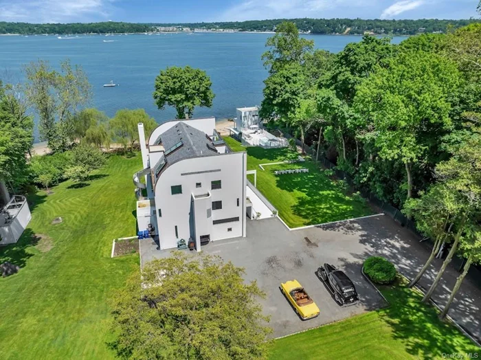 Discover unparalleled luxury in this Richard Meier-designed contemporary waterfront estate in Sands Point. This architectural masterpiece sits on expansive grounds offering 200 ft of breathtaking water views. The primary residence is a symphony of light and space. The home features floor-to-ceiling windows, open-plan living areas, and state-of-the-art amenities.  The estate includes a two-family staff house and a pool cabana. A standout feature is the 2 story boat/guest house, perfect for hosting or enjoying a serene retreat by the water. The historic ice house adds unique charm and ample storage, while the carriage house provides space for up to seven cars with a lift.  Outdoor living is equally impressive, with a sparkling pool offering panoramic views and a tennis court for athletic pursuits.  This extraordinary property harmoniously blends modern design with the natural beauty of its waterfront setting, offering an unmatched lifestyle of luxury, comfort, and exclusivity.