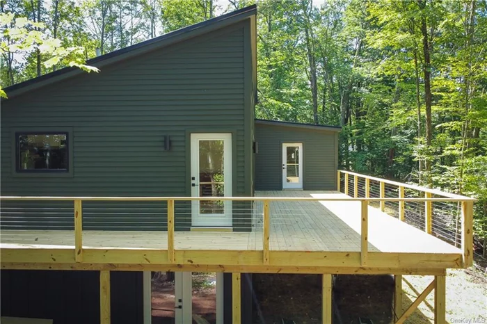 Welcome to 387 Hubert Road! This three bedroom, two bathroom soon-to-be-completed home sits just outside of the village of Jeffersonville in the Western Catskills, just over two hours from NYC. This elevated ranch is entered from the generous deck, which wraps around three sides of the home. All that space provides plenty of room for outdoor cooking, dining and relaxing surrounded by mature trees and seasonal ridge line views. Moving inside through the primary entrance, you&rsquo;ll find yourself positioned between the well-equipped kitchen and the airy main living space. In the kitchen you&rsquo;ll find marbled white granite counters atop shaker-style cabinets, plus ample open upper shelving. Stainless appliances include a 5 burner propane range with hood, refrigerator and dishwasher. Above the sink, the picture window nicely frames the bucolic surroundings. The convenient island is an ideal coffee station and provides some visual separation from the rest of the communal space. Moving into the main living area, you&rsquo;ll find that the double sliding doors and a large picture window highlight the beautiful surrounding landscape and allow for an abundance of natural to flow through. A cozy wood stove anchors the dining area, and provides another delightful focal point. Down the main hallway, you&rsquo;ll encounter the first of two guest rooms. The vaulted ceilings throughout keep the space feeling open and inviting. The first full bath features black stone tile floors and a white tiled shower and tub combo. Built-in shelving offers convenient storage. The generous second bedroom offers windows on two sides, making the most of the natural light and scenic views. An l-turn off the main hallway leads you past double hall closets to the primary suite. A large picture window anchors the bedroom, and a generous en suite bath with soaking tub and glass and tile shower completes the space. A private entrance onto the terrace is another added bonus. A utility room with washer/dryer hookups plus several convenient closets complete the first floor. The lower level of the house features an unfinished full height basement space with walkout doors, accessible from the outside. Just a few minutes outside of Jeffersonville, you have easy access to some of our favorite stops for local provisions, like Jeffersonville Bakery and Sullivan Sundries. You&rsquo;re also just about fifteen minutes from both Callicoon and Livingston Manor! 387 Hubert is expected to be completed by end of summer 2024. Some interior photos are from a recently completed, similar project.