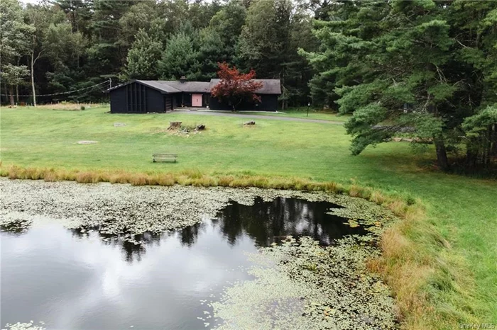 Your very own slice of Sullivan County in Eldred, NY a charming compound where modern convenience meets the serenity of country living. This spacious, recently renovated mid century home is just waiting to impress, with its sunken living room that adds a touch of retro chic and large windows that flood the space with natural light. All under two hours to NYC.  Upon entering, you&rsquo;ll catch a glimpse of the sunken living room and large sliding doors to the wooded back yard from the bluestone tile foyer. The kitchen - in its original 1970 glory - has a charming dining nook where you can entertain your dinner guests. The formal dining room features corner windows that look onto the ferns. Step down into that living room where you&rsquo;ll find room for your library on the massive shelves under the moody light of the fireplace and wood paneled ceiling. The brick fireplace with large stone hearth sets the scene for late night conversation. Down the hall, you&rsquo;ll find two large bedrooms that share a large, gut renovated bathroom. The primary suite, which has it&rsquo;s own walk in closet and renovated en suite bathroom, also has those large corner windows for looking out into the forest. No need for a TV! No two bedrooms share a wall for ultimate privacy. The partially finished basement offers a second fireplace and fun entertaining space for your guests. Not to be missed: the attached garage is ready to pamper your car, keeping it cozy and dry, no matter what the weather throws at it.  The guest cottage is a cozy retreat, perfect for hosting friends and family who&rsquo;ll be delighted to have their own private space. It&rsquo;s just the right size for them to enjoy your hospitality without being in your personal space.  Outside, the property offers a seasonal stream and a swimming pond ideal for those moments when you want to reconnect with nature or simply enjoy a quiet afternoon by the water. It&rsquo;s the perfect setting for embracing the laid-back lifestyle you&rsquo;ve been dreaming of, with just the right amount of sophistication and comfort.  Eldred offers a rural, wooded landscape that is almost pacific northwest in appearance with lots of evergreens and big open skies, peppered with large lakes and streams across the terrain. A brief drive to hot spots like Narrowsburgh, Bethel, Highland Lake, White Lake, Forestburgh, and Cochecton makes Pond View Compound your basecamp to all the hiking, swimming, fishing, concerts, shops, and restaurants that Sullivan County has to offer. This location is ideal as a weekend getaway, co-primary home, or full time residence. Welcome to your new home, where the country charm is balanced with mid century modern flair.