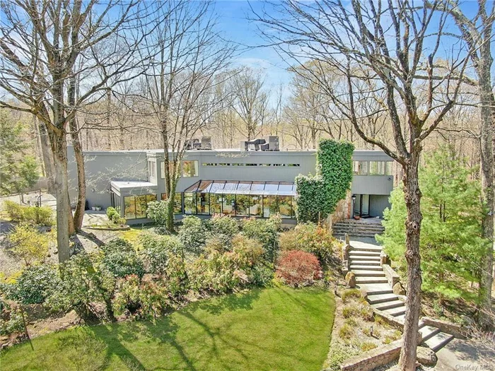 Mid-century modern home lovers will appreciate this 1979 contemporary, designed by Chappaqua architect, Charles Napoli as an homage to Frank Lloyd Wright. Set on 1.35 acres, this 5 BR, 5.1 BA home has walls of windows showcasing the lush property and mature trees. The open plan of the house flows naturally with a grand, open living rm to dining and eat-in kitchen w/ sliders to patio. The great room leads down to the den and additional lower level. A playroom with custom built-ins, guest suite w/ bathroom, gym w/ door to garage and plentiful storage, complete this level . The 2nd floor includes a large primary suite w/ office, dressing area, walk-in closet and beautifully updated bathroom. There are 3 more generously sized bedrooms and 2 bathrooms plus a sitting room. Outside, enjoy a large patio overlooking the terraced gardens and private backyard adjacent to over 20+ acres of town-owned land.