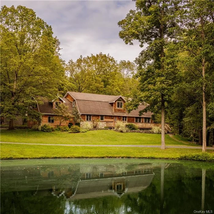 This gambrel roof Dutch Colonial style home is privately sited on 12+ acres overlooking a pond. Up a country drive under a beautiful canopy of mature trees, enter the home along the full length front porch. There is a kitchen with large pantry, dining area and 1/2 bath in the center of the structure. Two bedrooms and a full bath, laundry and mud room accessed via the attached 2 car garage are on the west side of the home. To the east, find a double height living room and stone faced wood burning fireplace, with sliding glass doors to the patio. Upstairs find a den, an office, a primary suite and bonus room over the garage. Over 3, 000 square feet of living space, refinished wood floors and a neutral palate define the interior. Outside enjoy nature and privacy conveniently located close the the Taconic State Parkway, halfway between the popular Villages of Rhinebeck and Millbrook, NY.