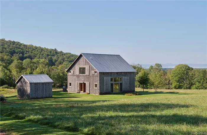 This stunning barn was moved to the most ideal spot on this scenic, rolling parcel, reimagined into a warm and welcoming home. In spite of its rustic wood paneling, there is a distinctive modern sensibility to the design. The Great Room&rsquo;s dramatic windows open onto multiple and varied views on three sides, framing bucolic tableaux. Doors open onto the rear patio which has a delightful siting, looking down over the pond. The over-sized kitchen island includes a built-in gas stove, farmhouse sink and barstools, while 2 recessed pantries offer extra storage. There is a generous lounge area with a corner wood stove. Off the wide entrance foyer a mudroom and laundry are followed by a powder room. Stairs lead to a catwalk that lends a treehouse feel, providing access to the 3 BRs and to a shared full bathroom with tiled shower. The primary BR enjoys the desirable spot at the end enjoying panoramic views. A soaking tub sits by the window, and you&rsquo;ll be charmed by the sink and shower nooks.