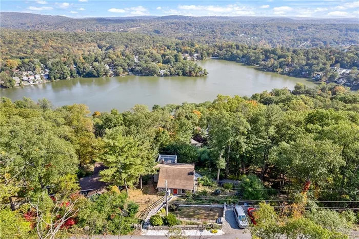 Experience breathtaking mountain and lake views from this unique, modernized log-style home. Nestled high above in a charming Lake Peekskill neighborhood, this two-family residence boasts stunning vistas of Lake Peekskill. Once the home of renowned artist Theodore Haupt, known for his work in the New Yorker and various New York galleries, the home features his artistic touch, including eye-catching totem pole supports. The spacious second-floor unit offers access to a large deck perfect for soaking in the incredible scenery, while the lower-level unit includes a generous patio for enjoyment. With ample parking and room for outdoor gatherings, this property is ideal for entertaining. Both units come with cozy fireplaces for winter warmth. The possibilities are endless: live in one unit and rent the other, seize a great investment opportunity by renting both, or explore the potential to convert it into a single-family home.