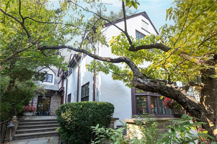 Nestled in the Spuyten Duyvil section of Riverdale, this 1925 classic Tudor home, with beautifully maintained classic architecture, stucco and stone details, casement windows, slate roof, copper roofing over the bay window, and stone detail around the windows with hand hewn wood accents, is surrounded by beautiful landscaping. Enter this beautifully maintained home from the east via wide stone steps leading to a stone patio, bringing one to the private south facing front door. The property is set back and elevated from Netherland Avenue affording additional privacy. This large classic home is a symphony of details that will enrich your living for years to come. Meticulously cared for, many original features are in place throughout the home with practical upgrades such as high velocity central air conditioning, and a renovated windowed kitchen with a separate dining nook.  Enter the generous and wide tiled Foyer with elegant stairs and double height windows at the first landing, flooding the Foyer with natural light. There is a Powder room subtly tucked under the landing on the first floor. The owners&rsquo; favorite room, The Great Room, a Sunken Living Room so large that you almost don&rsquo;t notice the Grand Piano in the room, showcases the wood burning Fireplace with original wood mantle, the grand eastern Bay Window, beamed ceilings, beautifully refinished wood flooring throughout, and picture moldings around the entire living room. Every casement window is original and has been meticulously cared for. The elegant formal Dining room has entry windowed gated doors with original hardware, leading to the front and rear stone Patios. The huge eat-in Kitchen with a peninsula is a Chef&rsquo;s dream, with several windows, high end appliances, bountiful granite counters, storage cabinets galore, and a large Dining area for everyday home cooked meals. There is a door to the patio from the kitchen for those outdoor dining occasions. The stairway to the second floor features custom railings with the original iron design and wood trim, which leads to a large three windowed landing and 3 Bedrooms and 2 full bathrooms. The sunken primary Bedroom elevates the prewar charm. The double exposure with an east-facing window having 4 panels, along with hardwood flooring, brings you back in time. The primary bedroom is equipped with 3 closets, one of which is a walk-in, and a nook for your dresser. The recently custom renovated ensuite bathroom, with subtle mosaic tiled flooring and full height glassed shower, has a vanity with under-mount sink coordinating with the mosaic coloring and design. The two additional bedrooms are generous and have two closets each and windows on 3 sides. The finished basement is equipped with full washer and dryer, a full bathroom, as well as a utility room with a new gas-fired hot water tank, storage areas, and a garage that has been converted to a music studio by the owners. There is a cement and inlaid brick 2 car driveway in front of the property.  Riverdale is just 10 miles from midtown with the Spuyten Duyvil Metro North Railway station nearby putting you in Grand Central in 25 minutes. There are local buses to the 1, 4, and A trains. The 1 train is just 12 minutes to get to through Ewen Park. There are express buses to midtown east and west, and a Wall Street express bus Monday through Friday. BxM1 and BxM2 express buses to the east and west sides of Manhattan, and the BX10 and BX20 buses from Kappock Street. The Bx20 connects to the A train. The Bx10 goes directly over to the Bronx Science high school.The Henry Hudson and Deegan Expressways are also close by. Spuyten Duyvil shops are nearby, as well as Central Riverdale where more shops, restaurants and services flourish. There are 2 colleges and several public and private schools in the area.