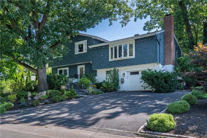 Only 1 mile from the Crestwood Train Station, this modern home is a one of a kind nature oasis that seamlessly blends fabulous outdoor and indoor spaces. The split-level layout offers an open-concept main level with a vaulted ceiling, sky-lights and a wall of sliding glass doors that provide a beautiful view of the backyard and connect to a large deck. The bright kitchen features a large 8ft island, a unique lighted quartzite waterfall top, stone backsplash, and 2 pantries. 3 bedrooms and 2 bathrooms occupy the top floor. The primary bedroom offers an en-suite bathroom and a floor to ceiling window with a Juliette balcony that allows you to enjoy the breeze, listen to the birds and watch spectacular sunsets above Crestwood. The lower level offers an entry foyer with a spacious closet, a large family room that doubles as an in-home theater,  an office, playroom or an additional bedroom. Solid wood pocket doors make it easy to transform the lower level to private guest quarters or a quiet office lounge. Sliding glass doors connect the space with a large bluestone patio, outdoor kitchen fully equipped for preparing meals and a flat backyard. You will be enveloped by nature and tranquility as the large .3 acre yard offers many cozy spaces for relaxing, playing and entertaining, a custom built play-yard for kids complete with a beautiful tree-house. Hard-wired landscape lighting and built-in outdoor speakers add to the magical ambiance. Features of the house include in-ceiling lighting, built-in speakers, video monitoring, a wood-burning fireplace, sprinkler system, concealed outdoor storage and shed, 2 large attics, high-end fixtures, low taxes, short distance to train, schools, the Bronx River bike path, shopping and many restaurants.