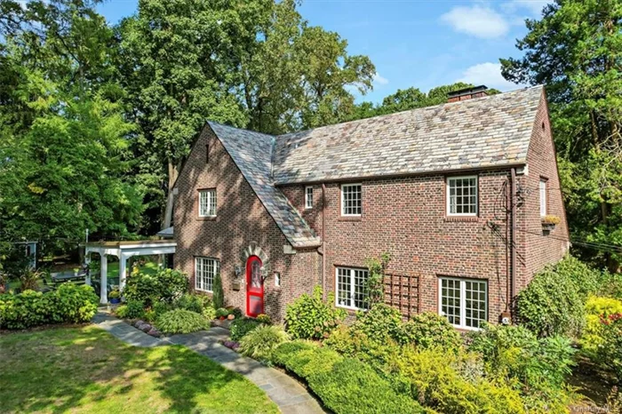 Enchanting! Come fall in love with this stunning brick Tudor in Sleepy Hollow Manor. The tingling will start at the red arched antique Dutch door entry. Sunlight invites you into the spacious LR with beautiful wood floors, a gas PFL and built-in bookcase. Remote and sensor controlled shades in the LR and sun-room move with the changing light. The adjacent sun-room with radiant heated floor is the perfect place for a your desk or to lounge with a book! The gourmet KIT with soapstone counters and white cabinetry boasts high end appliances, and farm sink any chef would feel at home here. The sitting area and dining room w/dual sided gas FPL open to the covered patio. A guest room with en-suite bath and PR complete the main level. The primary BR offers his/her closets and en-suite bathroom. There are 2 family BRS w/ Jack and Jill bath. The lower level is complete with private entry home office, gym and utilities. Perennial flowers surround the patios and yard. This is home!